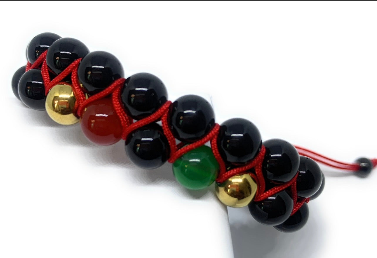 Bracelet with black beads, gold and red accents on a white background