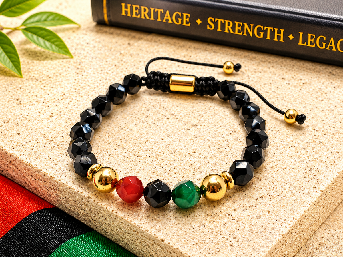 Beaded bracelet with black, red, green, and gold beads on a textured surface with a book in the background.
