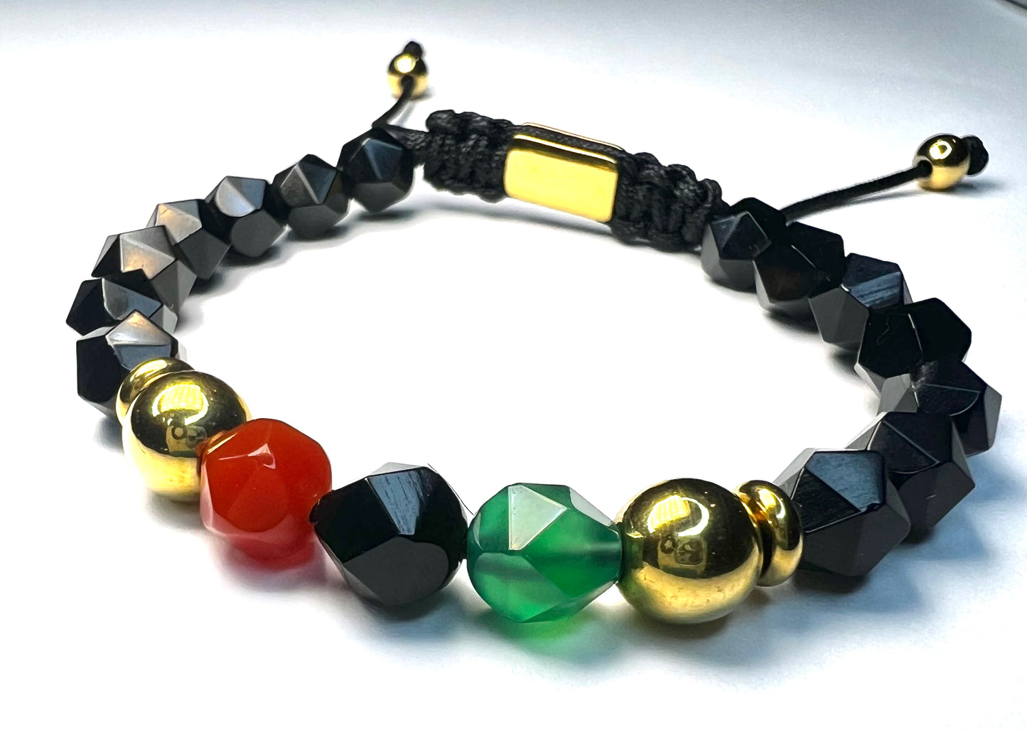 Bracelet with black, gold, red, and green beads on a white background
