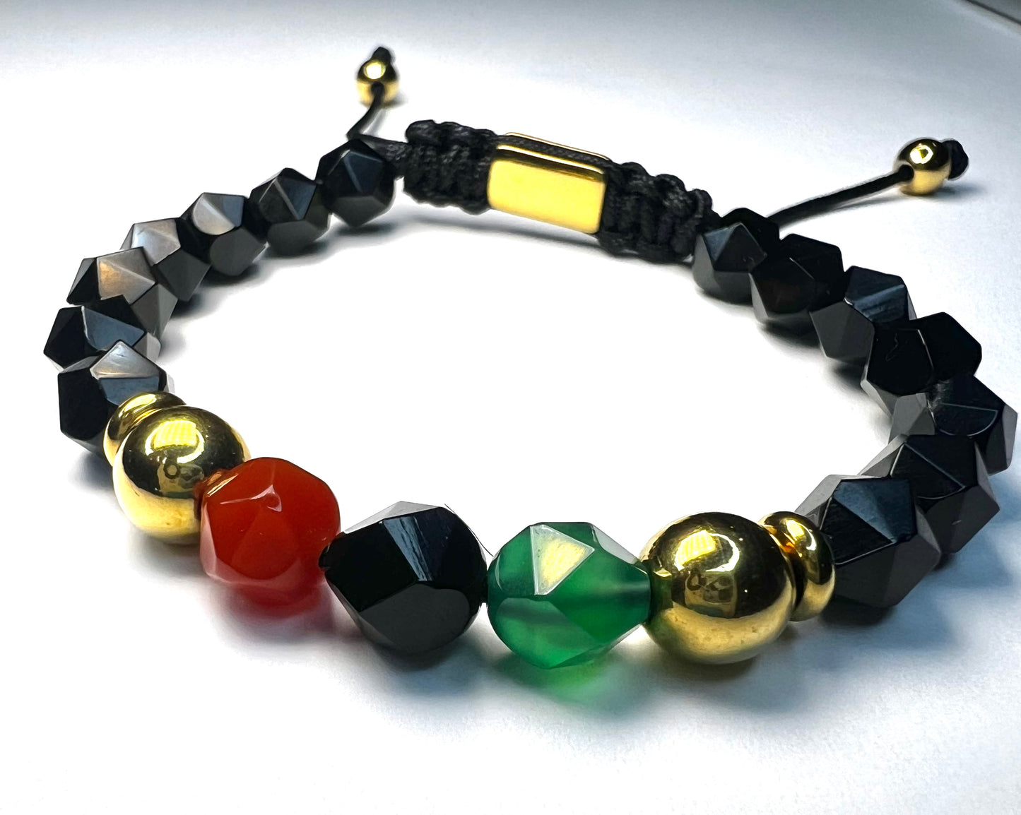 Bracelet with black, gold, red, and green beads on a white background
