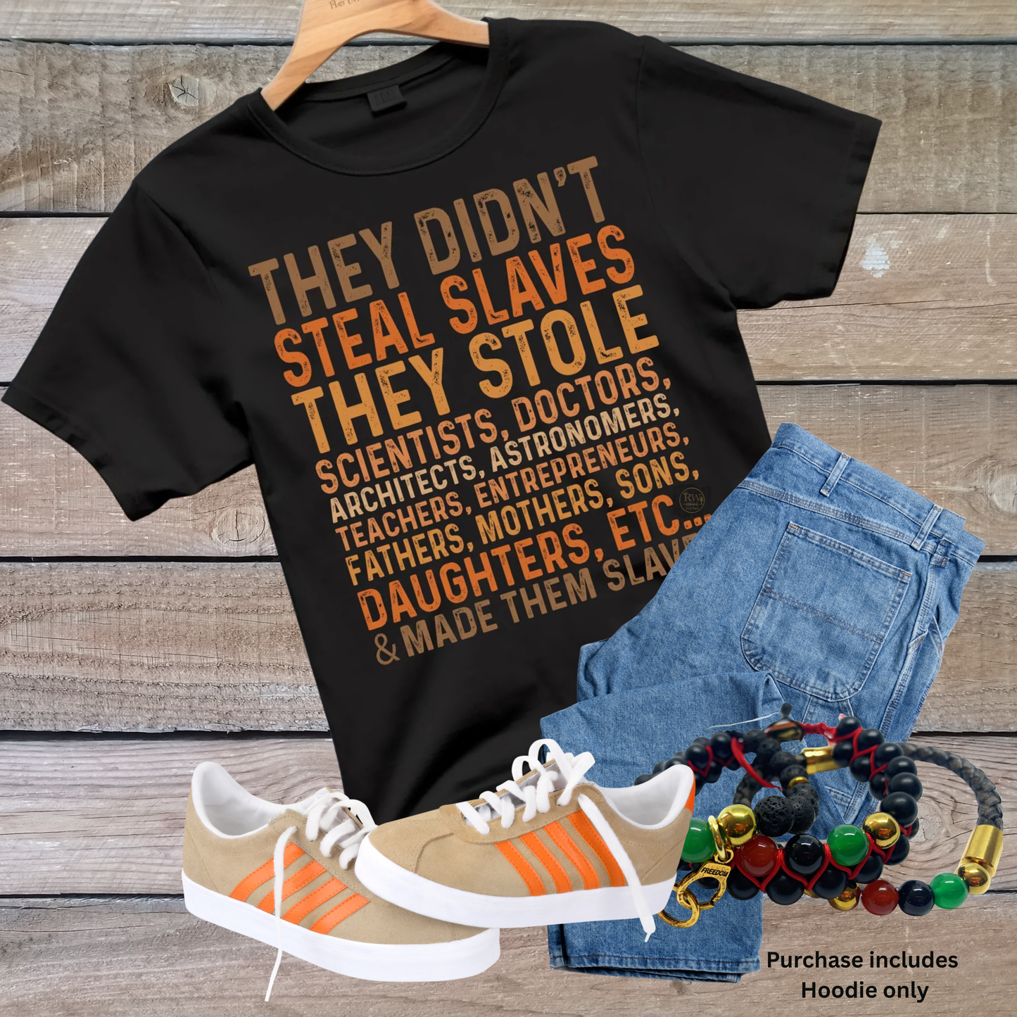 Black hoodie with text, blue jeans, sneakers, and bracelets on a wooden surface